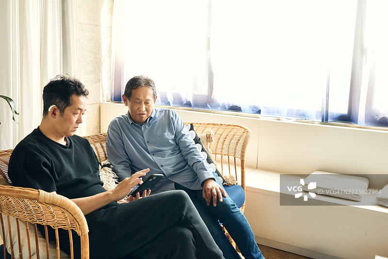 男人们在客厅沙发上放松，欢笑并用手语交流。图片素材