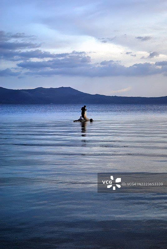 一个孤独的人在平静的水面上划着桨板。图片素材