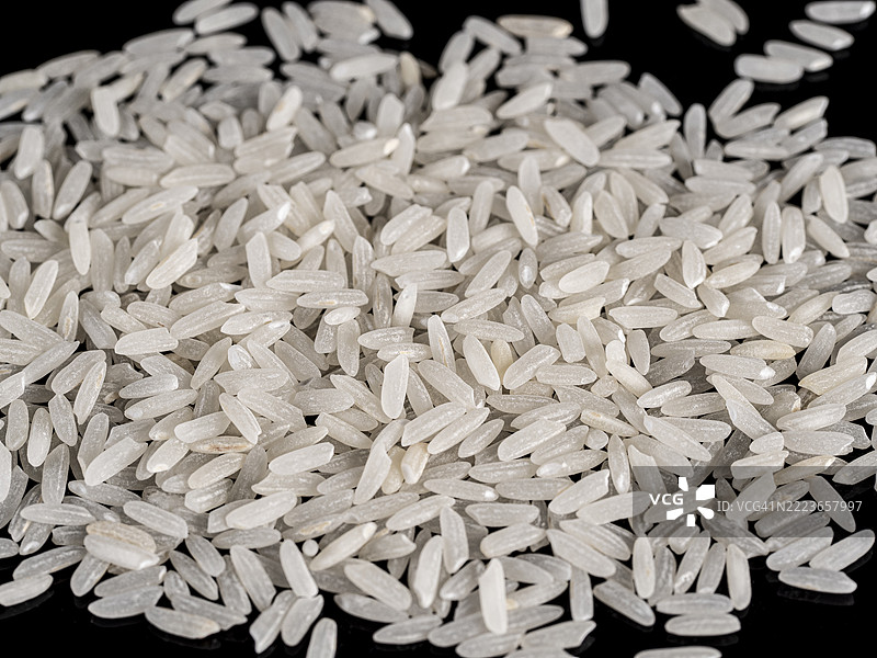 黑色背景上的一堆长粒米。图片素材