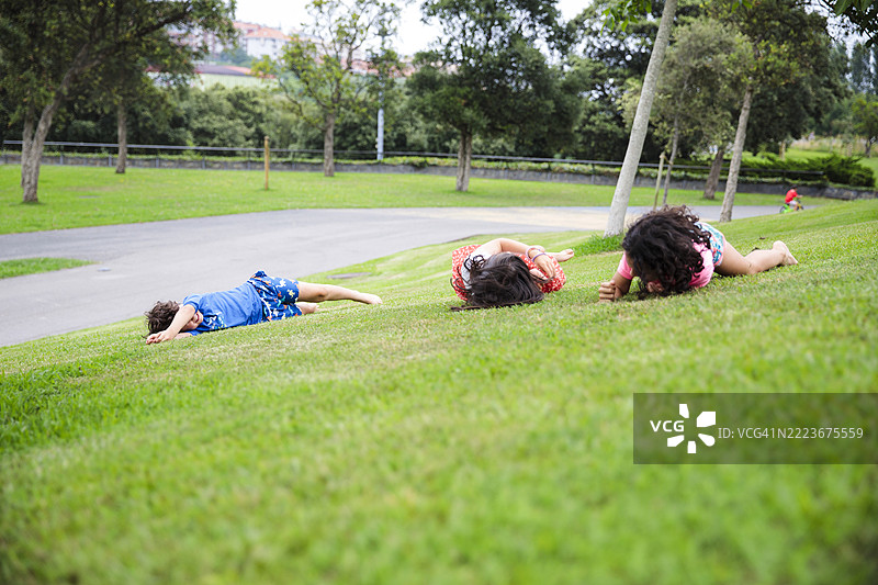 孩子们在公园的草地上玩耍，翻滚嬉戏图片素材