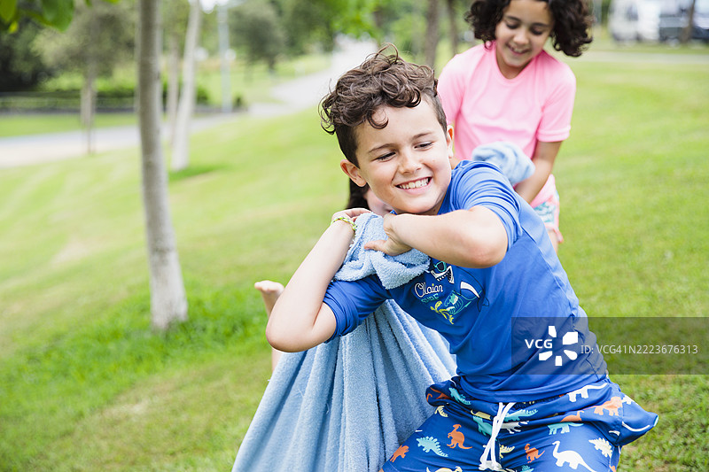 快乐的孩子们在公园里拖着裹在毯子里的朋友玩耍。图片素材