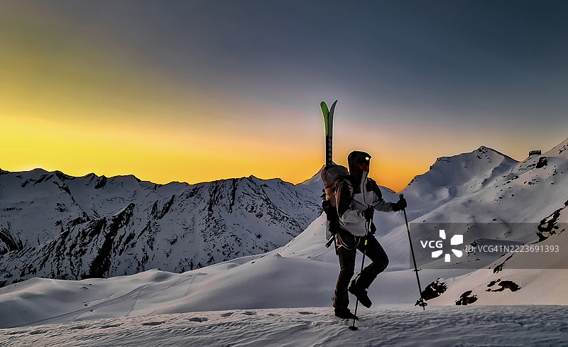 滑雪者在日落时分徒步攀登山顶图片素材