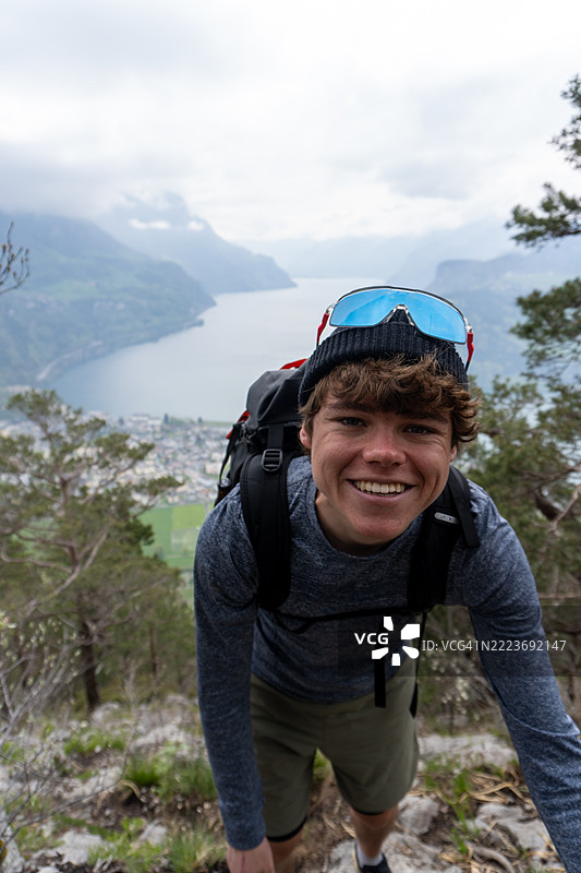 年轻男子在湖上方的山脊上攀爬图片素材