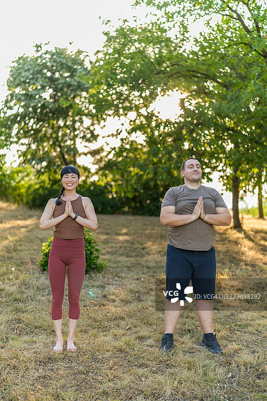 美丽的日本老师在户外瑜伽课上练习树式瑜伽。图片素材