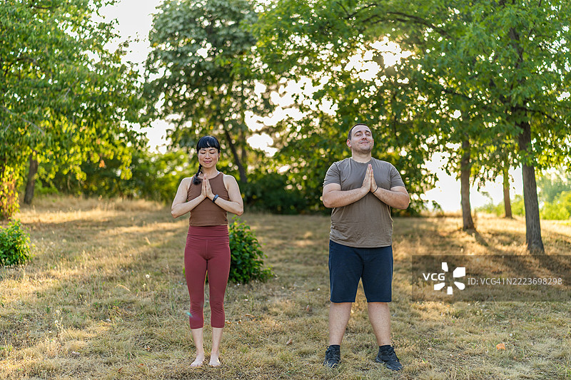 美丽的日本老师在户外瑜伽课上练习树式瑜伽。图片素材