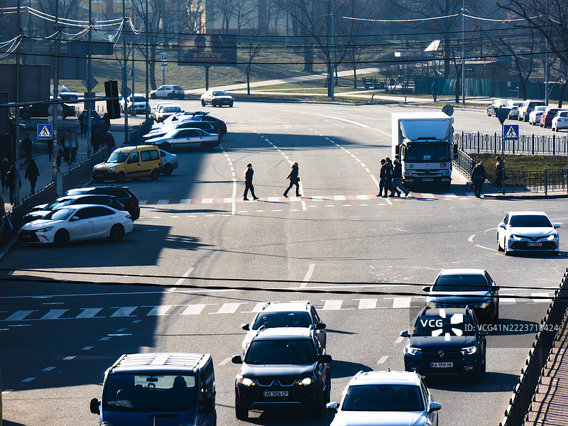 繁忙的城市交叉口，行人穿行，车辆在白天的街道上行驶图片素材