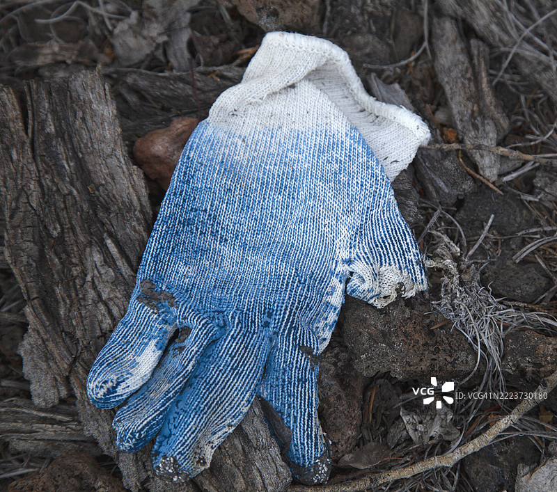 地面上丢弃的单只蓝色布工作手套特写。图片素材