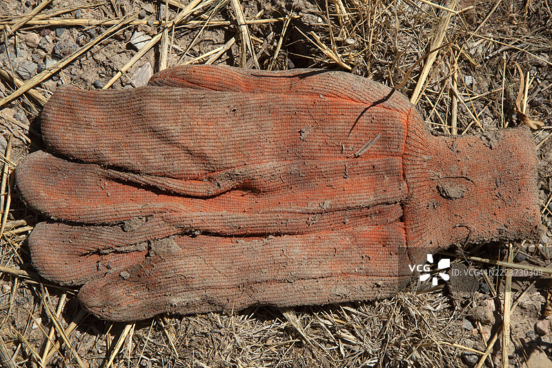 地面上丢弃的单只红色布工作手套特写。图片素材
