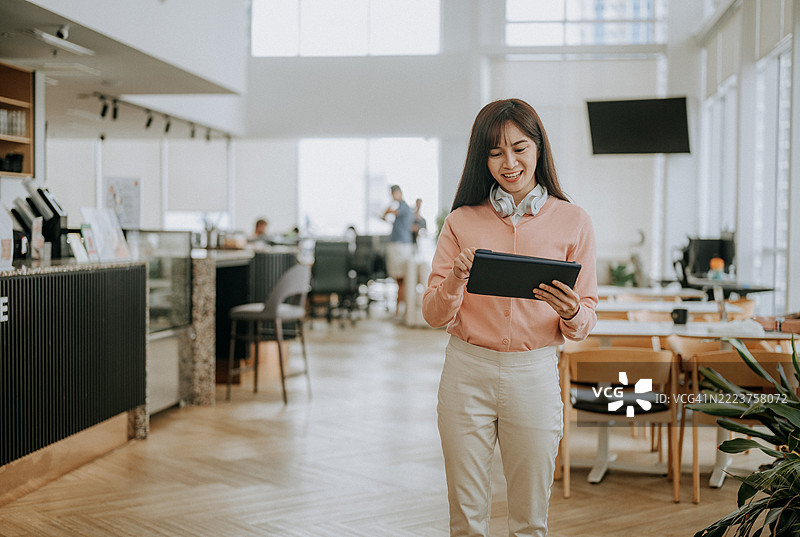 一位中国女商人在现代共享办公空间使用数字平板电脑的肖像图片素材