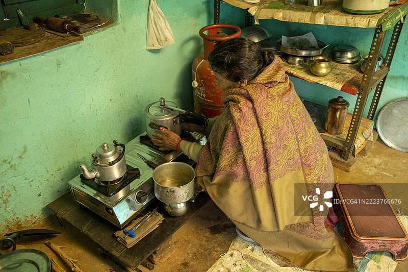 贫穷的印度乡村妇女在简单的农村厨房里用煤气灶做饭图片素材