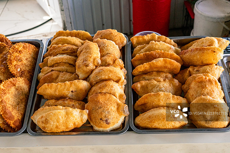 在吉尔吉斯斯坦的奥什市场上，新鲜出炉的萨姆萨摆放在金属托盘上。图片素材