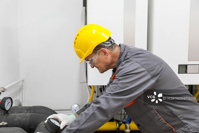 戴安全帽的工程师正在检查工业管道上的压力表图片素材