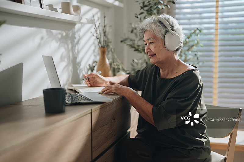 一位老年女性在家参加在线语言课程学习外语图片素材