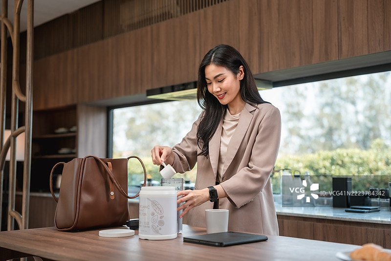 女商人在厨房准备蛋白质奶昔，准备上班。图片素材
