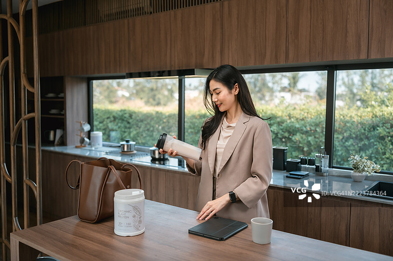 女商人在厨房准备蛋白质奶昔，准备上班。图片素材