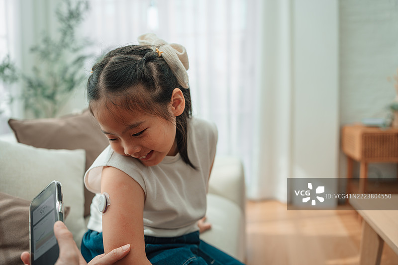 现代妈妈使用连续血糖监测设备检查女儿的血糖水平图片素材