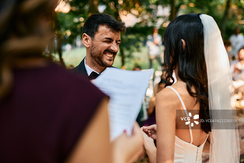 新郎在婚礼仪式上与新娘交换戒指时笑着图片素材