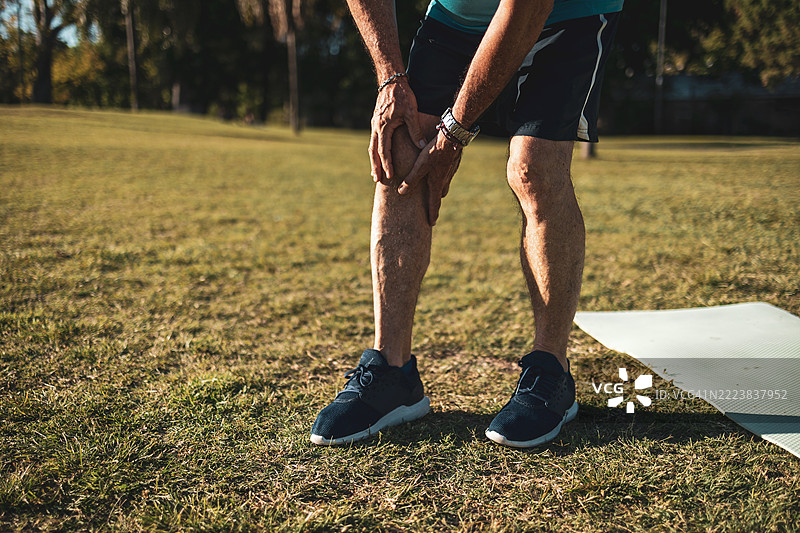 老年男性在户外锻炼时感到膝盖疼痛图片素材
