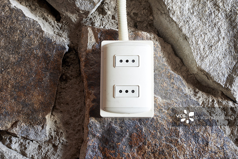 石墙上的白色双电源插座提供电力图片素材