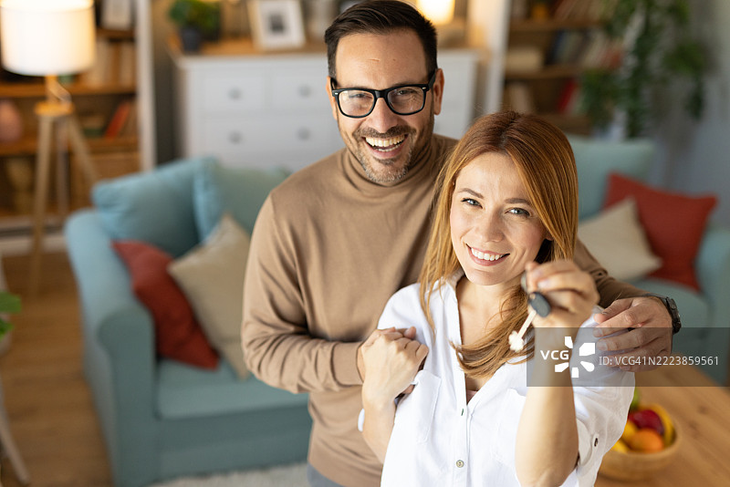 情侣在美丽的居住空间中庆祝新家，手持钥匙图片素材