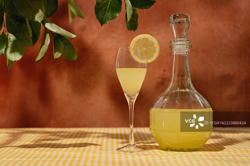 花园桌上摆放着自制的柠檬酒酒杯和水壶，桌布是黄色的。夏季花园。图片素材