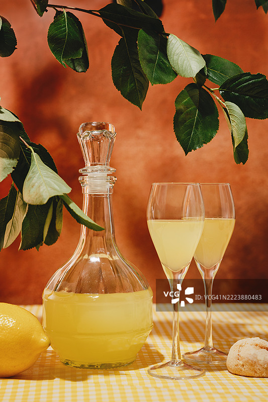 夏季花园里的花园桌上摆放着柠檬酒杯和柠檬饼干，桌布是黄色的。图片素材