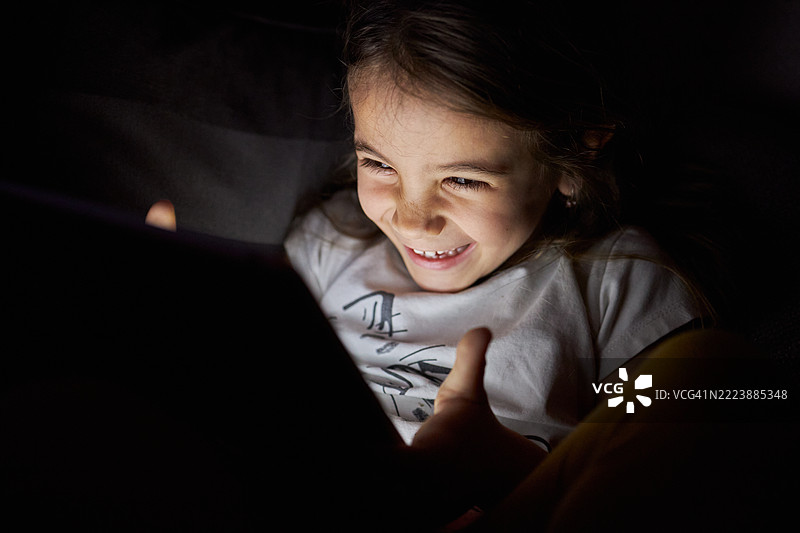 小女孩在夜晚使用平板电脑图片素材
