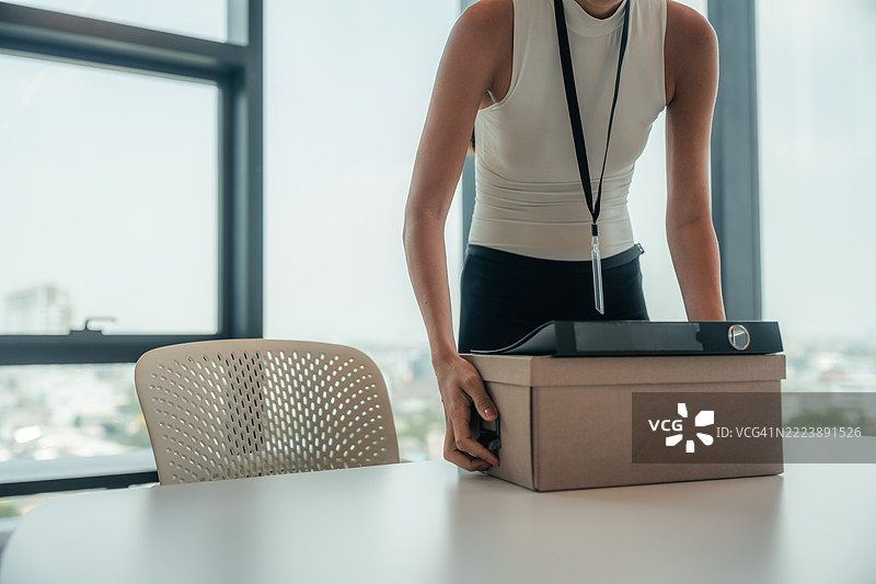 女性员工在安静地将个人物品打包进箱子，准备离开她的第一份工作。图片素材
