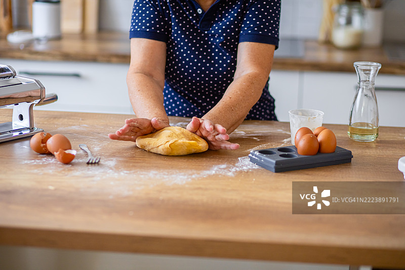 在厨房的木质台面上揉制新鲜意大利面团图片素材