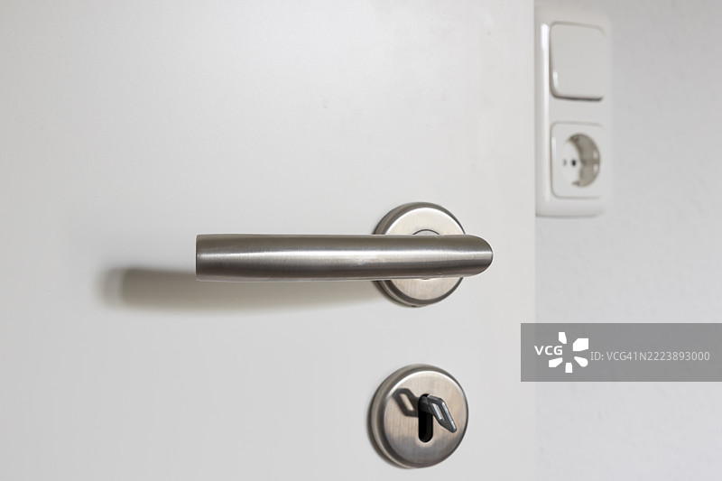 带有门把手和锁的门，背景中有电源插座和开关图片素材