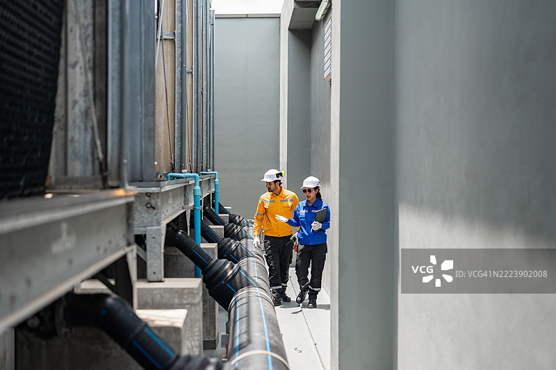 工程师在城市环境中监督工业屋顶管道图片素材
