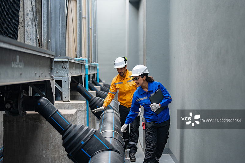工程师在城市环境中监督工业屋顶管道图片素材