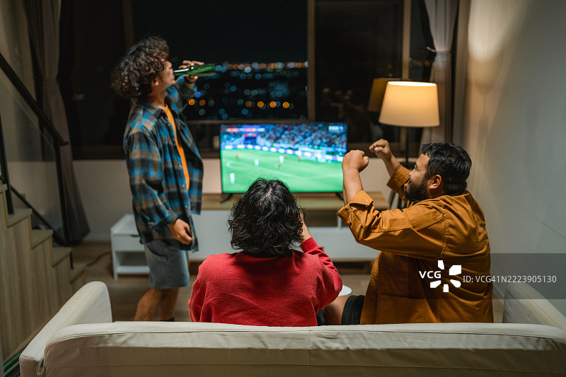 一群兴奋的足球迷在电视前欢呼庆祝，因为他们最喜欢的球队进球了图片素材