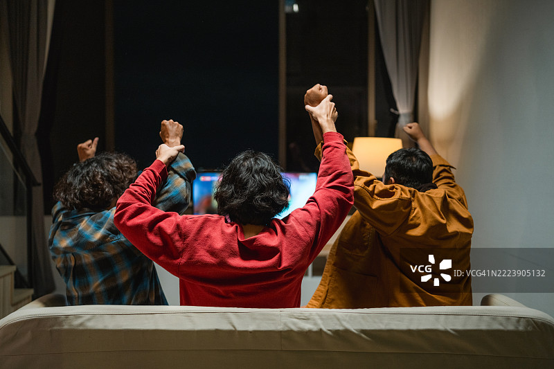 一群兴奋的足球迷在电视前欢呼庆祝，因为他们最喜欢的球队进球了图片素材