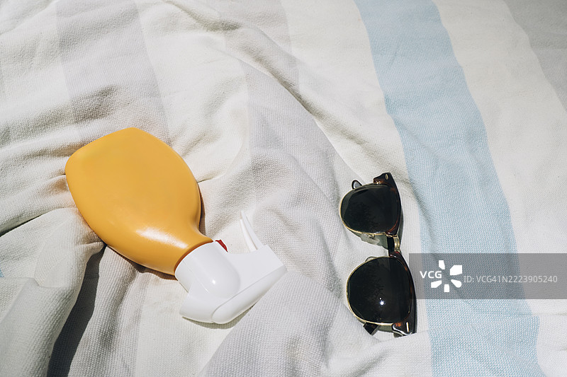 沙滩毛巾上的防晒霜和太阳镜：夏季阳光保护必备品图片素材