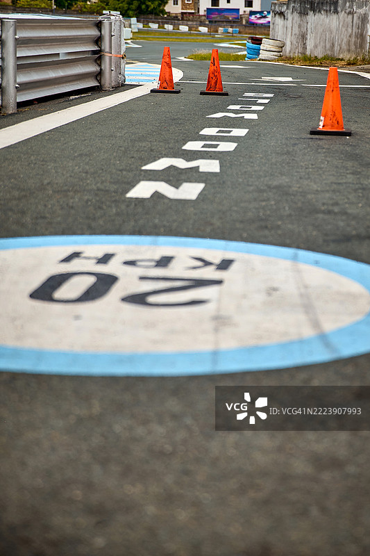 一条铺砌的跑道上有一个大圆形蓝边的“20 KPH”限速标志。图片素材