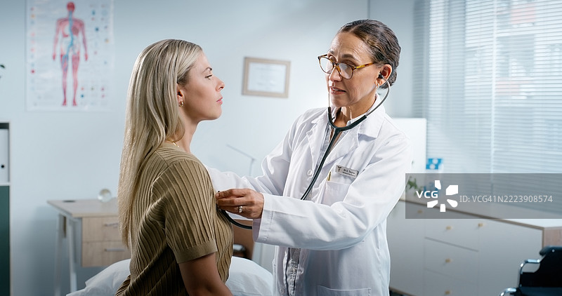 女性在诊所进行胸部检查，医生使用听诊器监测心跳和哮喘。患者与医疗工具一起聆听心率、健康评估和肺部测试。图片素材