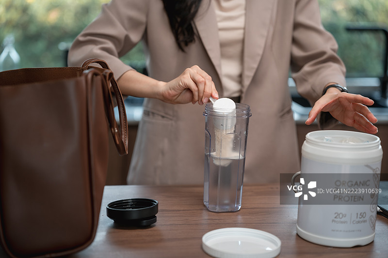 女商人在厨房准备蛋白质奶昔，准备上班。图片素材
