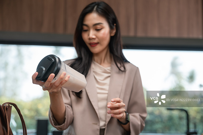 女商人在厨房准备蛋白质奶昔，准备上班。图片素材