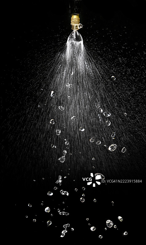 消防喷头，喷射出高压水流，背景为黑色。图片素材