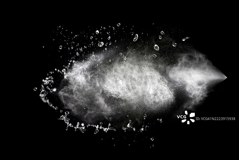 黑色背景上喷洒的水滴和水花的云朵，伴随着移动的水滴。图片素材