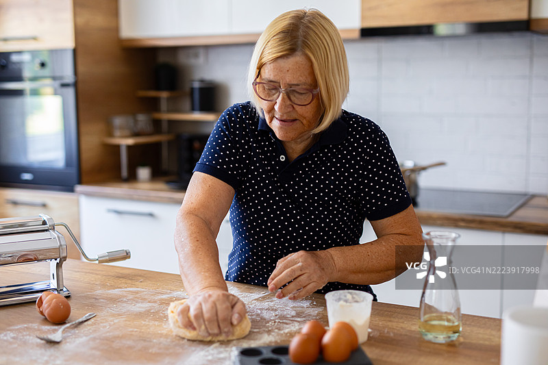 在厨房的木质台面上揉制新鲜意大利面面团图片素材