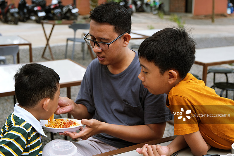 父亲与孩子们在户外桌子上共享美餐图片素材