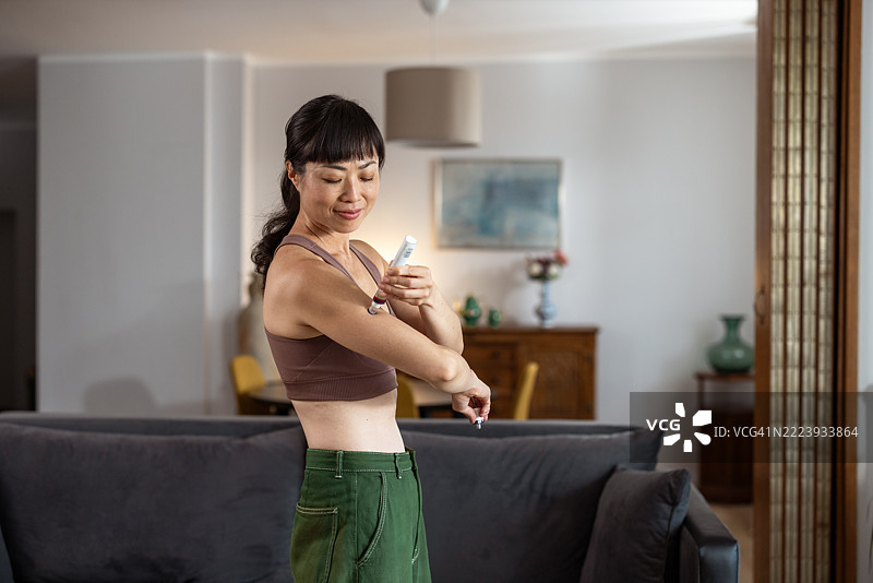 一位女性在家中微笑着进行医疗注射图片素材