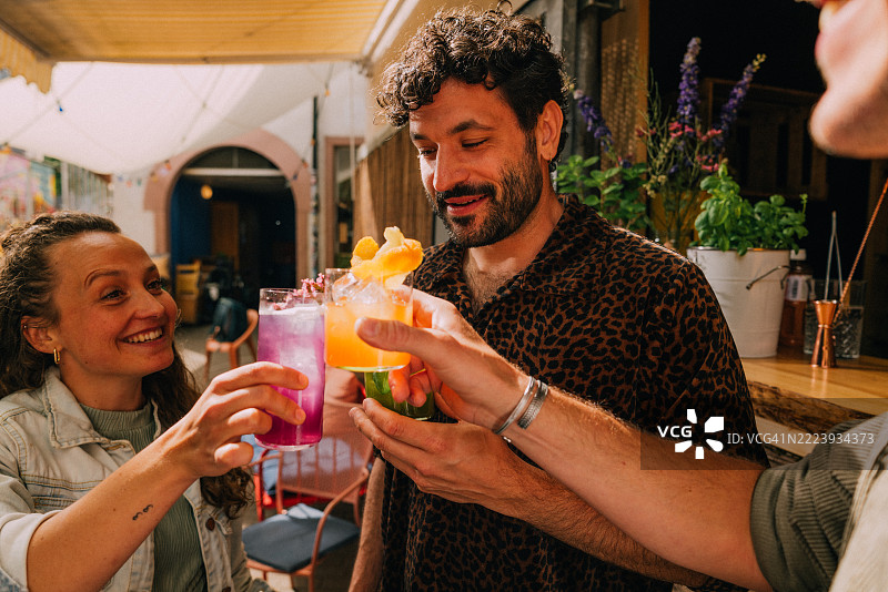 一群朋友在户外聚会上举杯庆祝，手中拿着五彩缤纷的饮料图片素材