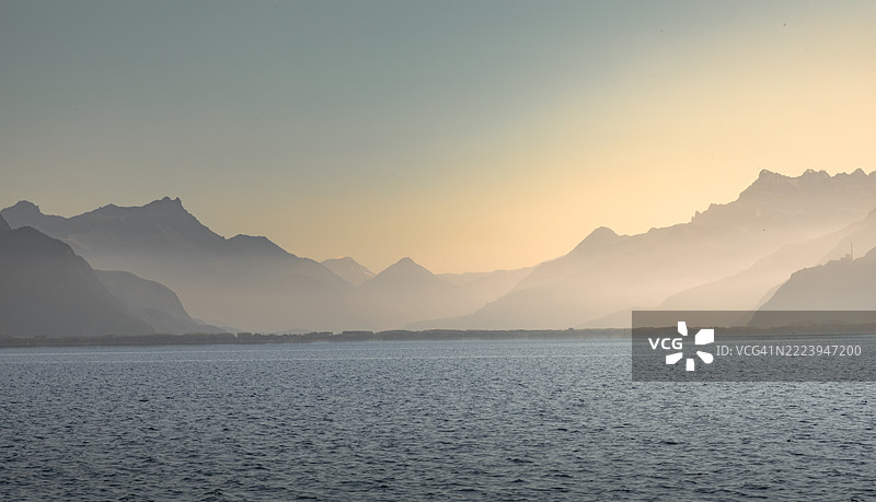 日落时分，清澈天空下的海洋与山脉美景，瑞士沃州维韦。图片素材