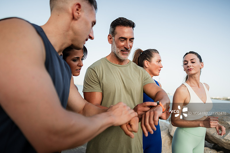 一群运动员在户外训练后查看智能手表图片素材