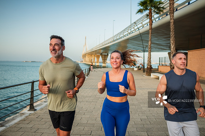 三个快乐的成年人在海边奔跑图片素材