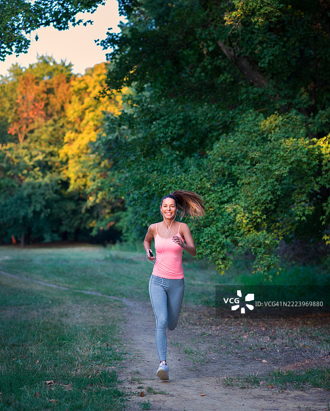 年轻的女运动员在夏季大自然中奔跑图片素材