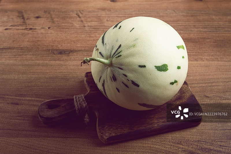 小型白色带绿色条纹的恐龙西瓜，放在桌子上，特写，无人。图片素材